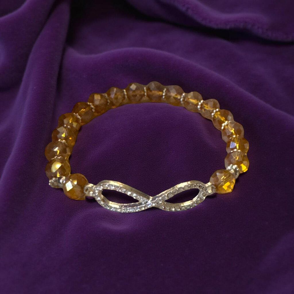 dazzling crystal infinity charm set against warm golden faceted beads, it’s the perfect piece to brighten up your look, whether you’re dressing up for a night out or adding a touch of sparkle to your everyday style.