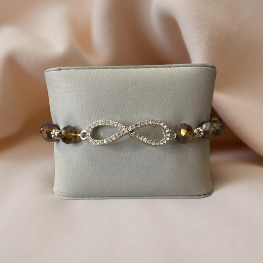 Sparkling rhinestone infinity charm at the center, framed by faceted bronze-toned beads that catch the light beautifully, this bracelet brings just the right touch of glamour to both everyday wear and special occasions.
 